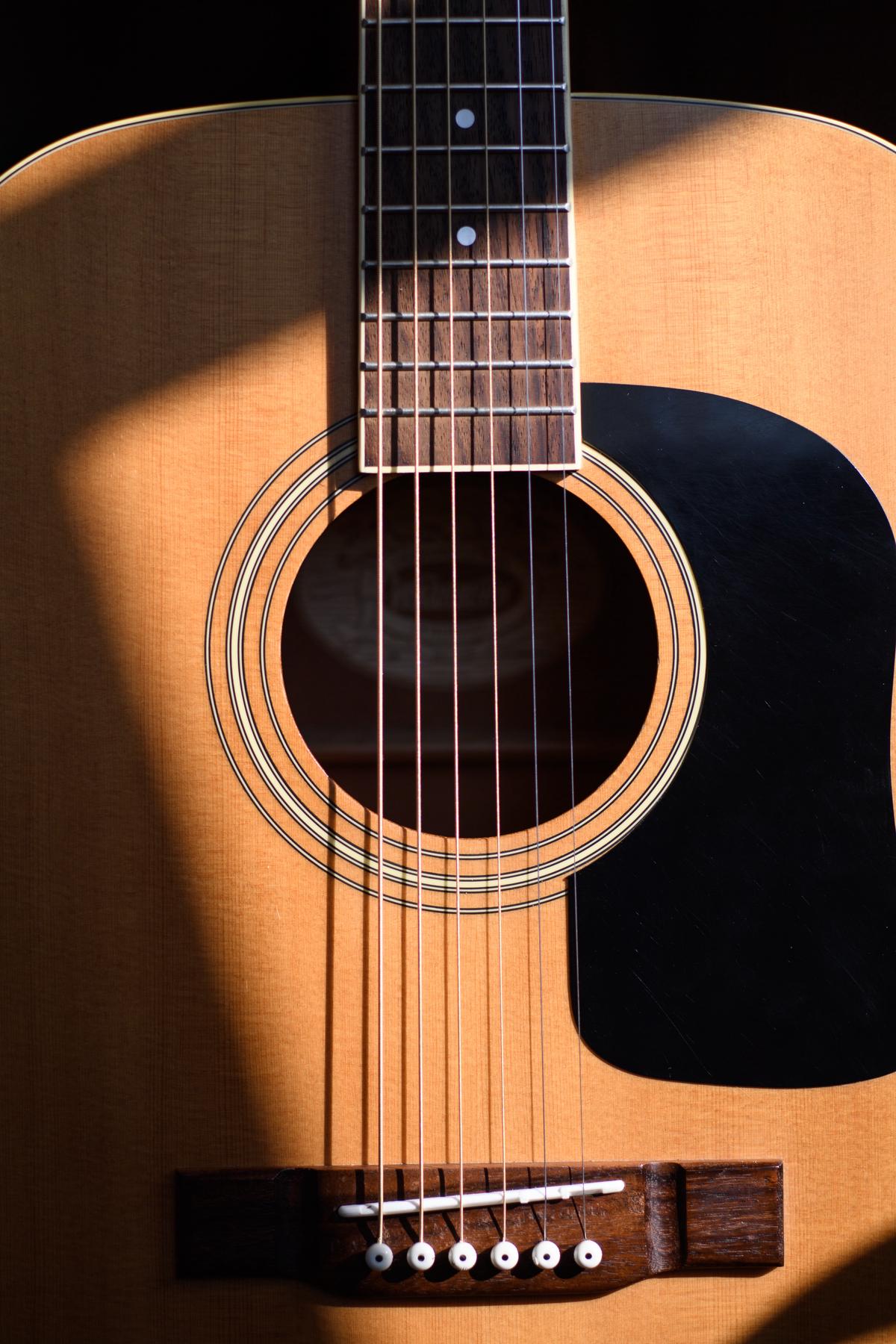 Illustration showing a person measuring the girth of a guitar with a tape measure